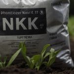 Мішок з добривом на природі, чітко видна формула NPK з числами та символами у м’якому розсіяному світлі.